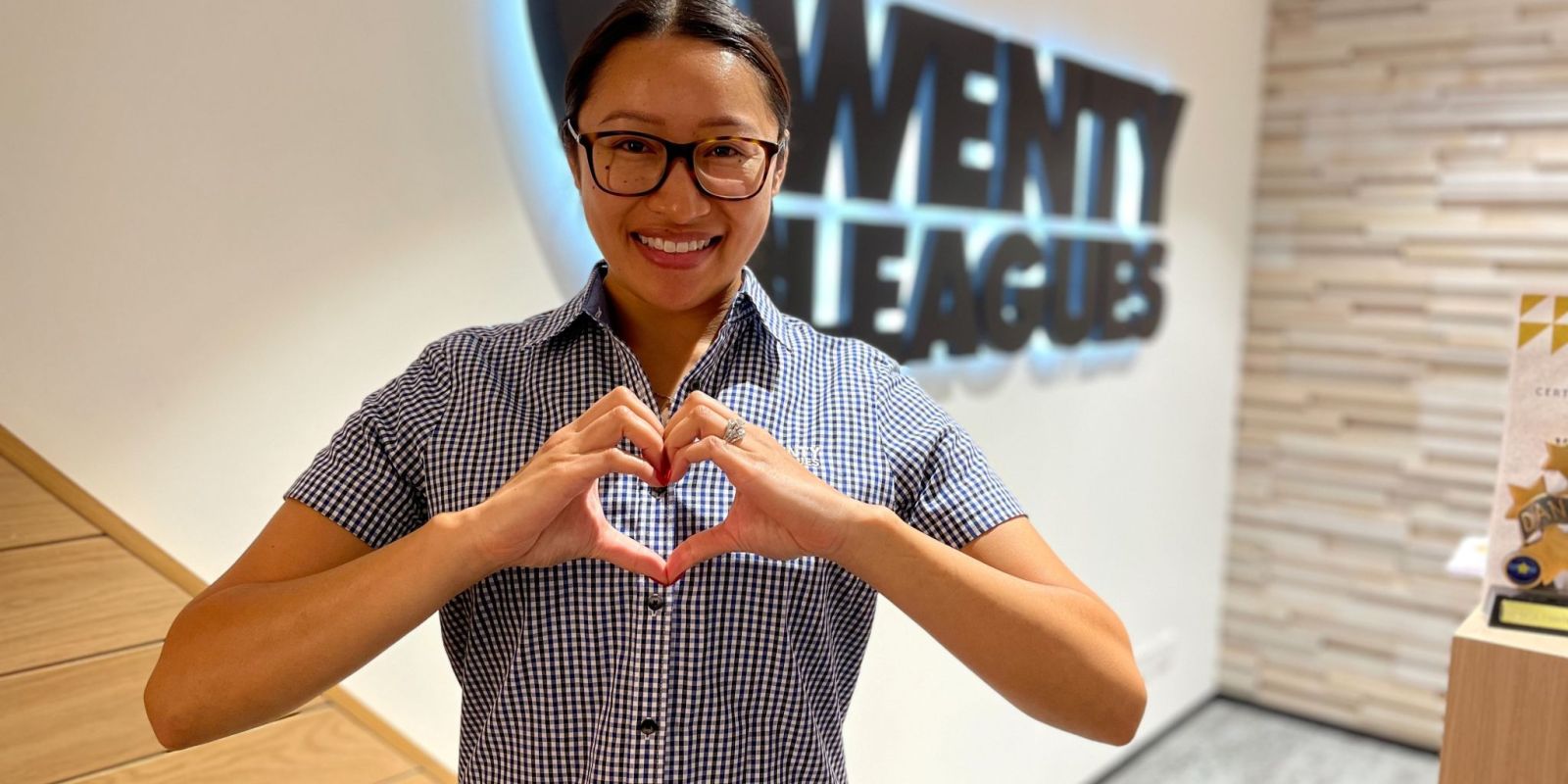 Staff member makes heart symbol with hands in front of club logo