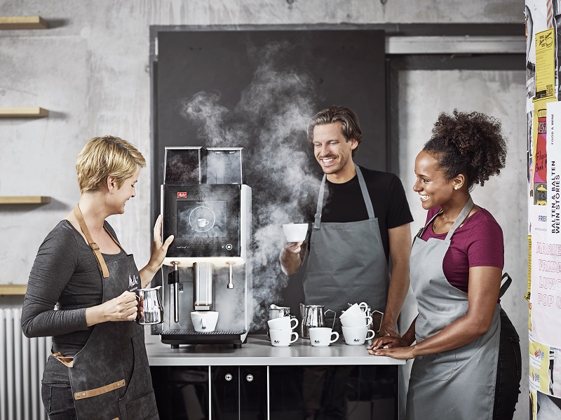 Baristas happily make coffee from a Melitta machine